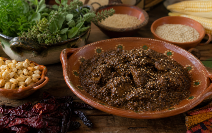 Mole de granillo del Istmo de Oaxaca servido en cazuela de barro, con maíz, chiles y hierbas alrededor