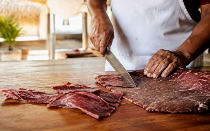Maestro tasajeador corta cecina artesanal de Yecapixtla sobre una mesa de madera