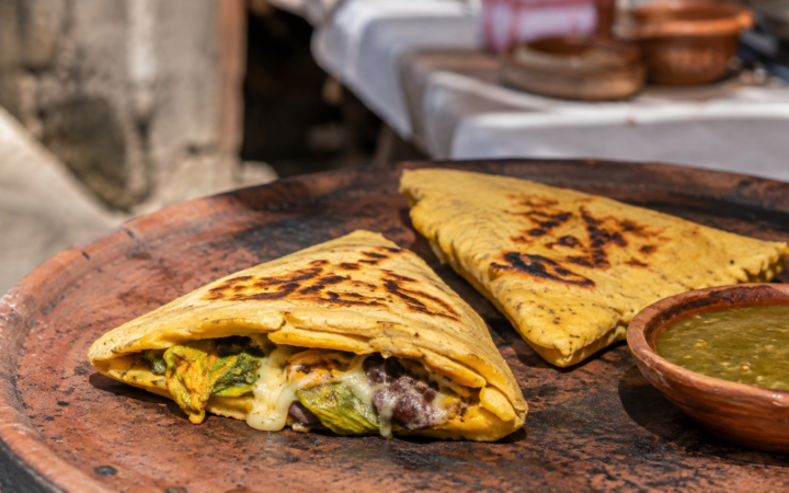 Itacates tradicionales recién cocidos sobre un comal de barro, acompañados de salsa verde