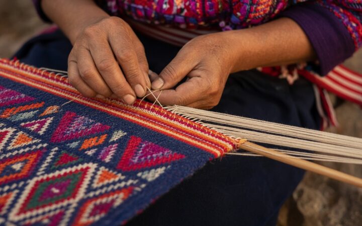 Manos que trabajan un tejido de colores en un telar.